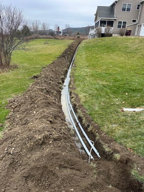 Trench with underground electrical conduits leading to a residential property by Clemens Electric in Averill Park, NY