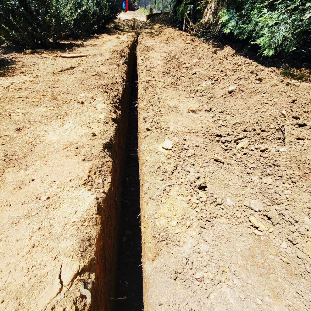 A deep trench dug in the ground, likely for underground electrical conduit installation by Corey N Craig Electric LLC in Charlotte, NC.