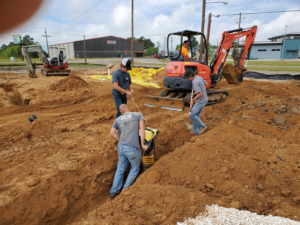 Workers, including one from ECS, performing underground electrical trenching on a construction site in Lake Charles, LA.