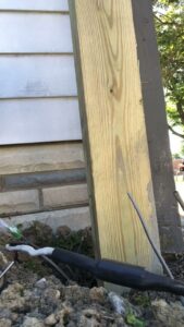 Electrical wires emerging from the ground next to a wooden post, indicating outdoor wiring work by Surge Electric LLC in Youngstown, OH.
