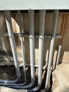 Electrical conduits emerging from the ground and running up a wall, installed by Rubio Electrical Innovations LLC in San Antonio, TX.