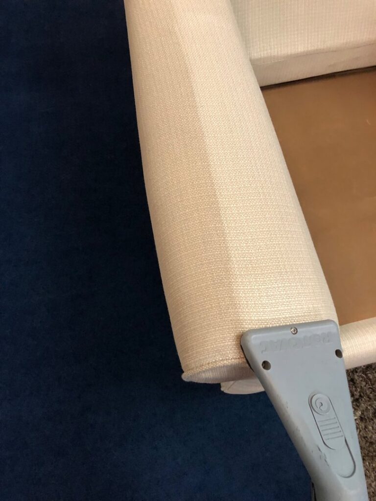 A professional cleaning tool working on an upholstered armrest, showing the cleaning process by JS Carpet Cleaning in San Jose, CA