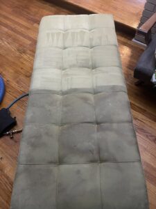 An upholstered bench, half cleaned to show the before and after, by Affordable carpet cleaning CO LLC in Montgomery, AL.