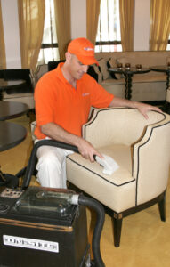 A technician from Rugsies.com performing professional upholstery cleaning on an armchair in North Miami, FL.