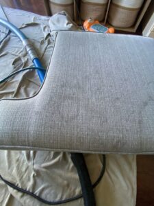 A close-up of a chair cushion being professionally cleaned with an upholstery tool by Imperial Carpet Cleaning in San Diego, CA.
