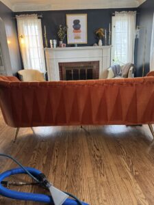 Upholstery cleaning equipment on a hardwood floor with a clean sofa in the background by 5 Alarm Carpet Care in West Allis, WI.