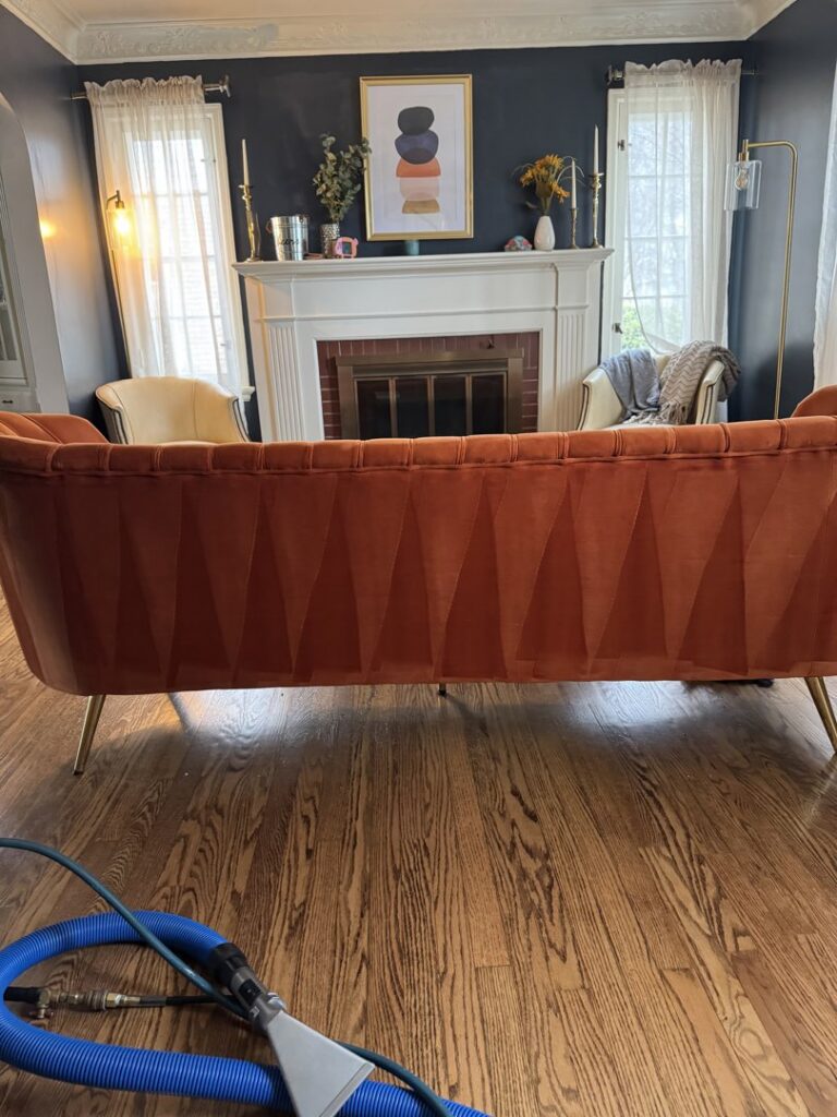 Upholstery cleaning equipment on a hardwood floor with a clean sofa in the background by 5 Alarm Carpet Care in West Allis, WI.