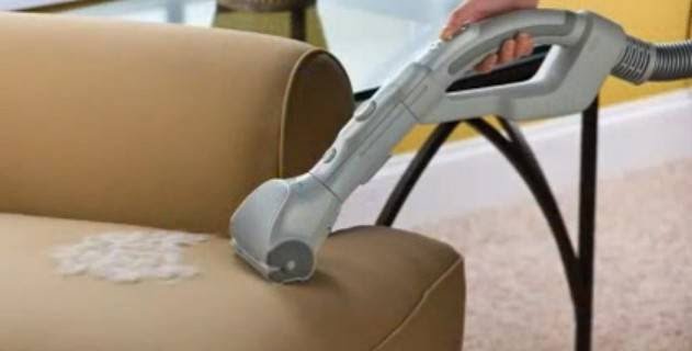 A professional cleaning a stain on a sofa with an upholstery tool at ABRA Chem-Dry in Green Bay, WI.