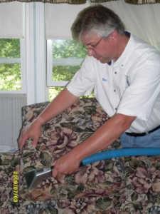 A professional performing upholstery cleaning service on a sofa at Dressler's Carpet and Upholstery Cleaning in Schenectady, NY