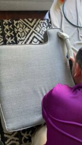 A professional performing upholstery cleaning on a chair cushion for Imperial Carpet Cleaning in San Diego, CA.