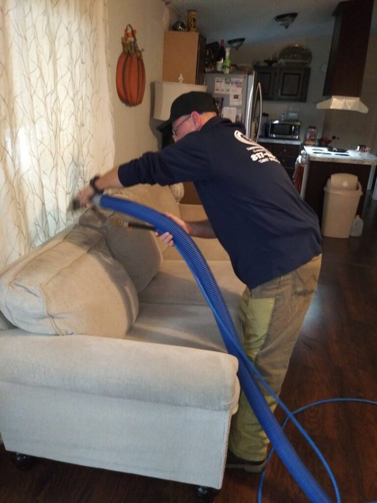 A KCclean technician providing professional upholstery cleaning service for a sofa in Arlington, TX