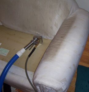 Professional upholstery cleaning in progress on a sofa by Hebert's Reliable Cleaning Solutions in Chicopee, MA.