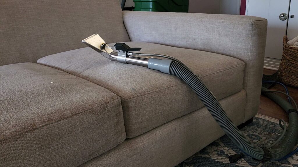 A professional upholstery cleaning tool being used on a sofa by Precision Chem-Dry Of DFW in North Richland Hills, TX.