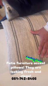 A professional cleaning a striped patio furniture accent pillow with an upholstery tool at Alex's Janitorial and Carpet Cleaning in Bakersfield, CA