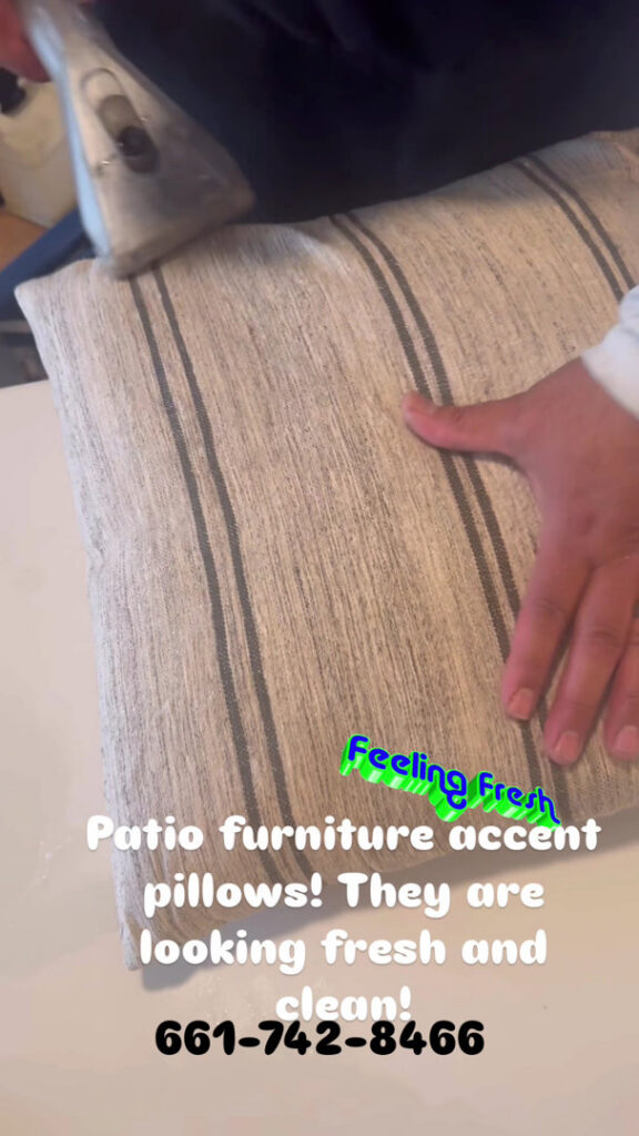 A professional cleaning a striped patio furniture accent pillow with an upholstery tool at Alex's Janitorial and Carpet Cleaning in Bakersfield, CA