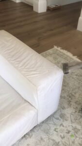 A professional cleaning the armrest of a white upholstered sofa with a specialized tool at Alex's Janitorial and Carpet Cleaning in Bakersfield, CA