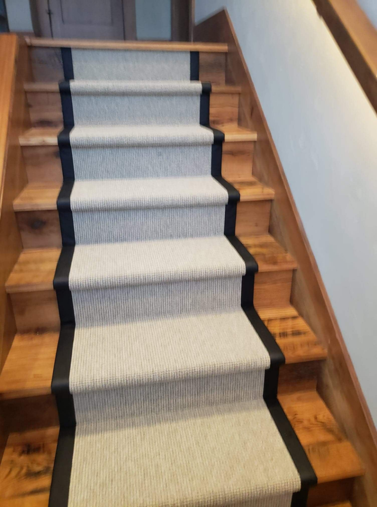 An upward view of custom carpet runners installed on wooden stairs by Altered Edge in Kalispell, MT