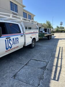 A US AIR service truck with a trailer transporting an old HVAC unit for disposal after removal in Baton Rouge, LA.