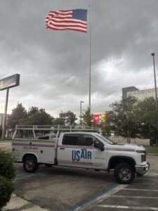 A US AIR service truck and van parked on a residential driveway, indicating an HVAC service or installation in Baton Rouge, LA.