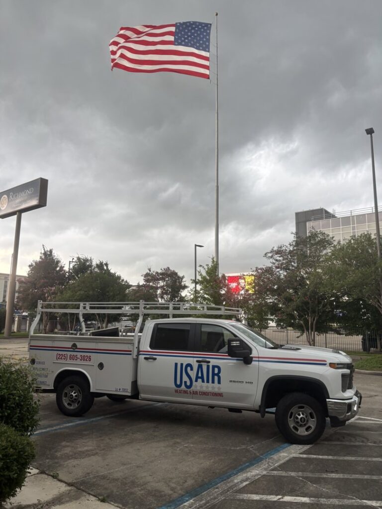 A US AIR service truck and van parked on a residential driveway, indicating an HVAC service or installation in Baton Rouge, LA.