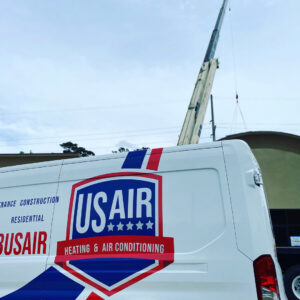 A US AIR service van parked at a job site with a crane in the background, indicating HVAC system installation in Baton Rouge, LA.