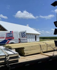 A US AIR service van and business sign at a construction site, indicating HVAC installation work in Baton Rouge, LA.