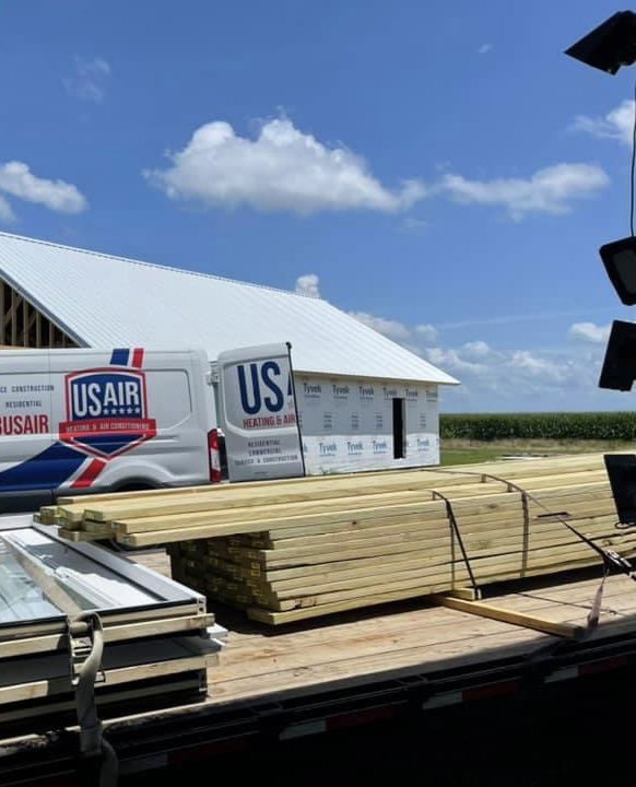 A US AIR service van and business sign at a construction site, indicating HVAC installation work in Baton Rouge, LA.