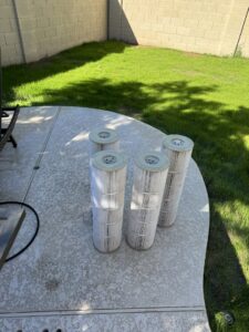 Used pool filter cartridges laid out on the ground, ready for cleaning or replacement by Pool Pals in Franklin, MA.