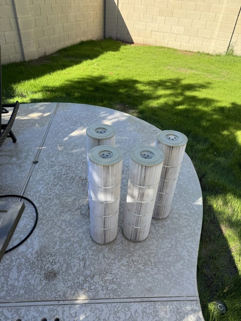 Used pool filter cartridges laid out on the ground, ready for cleaning or replacement by Pool Pals in Franklin, MA.