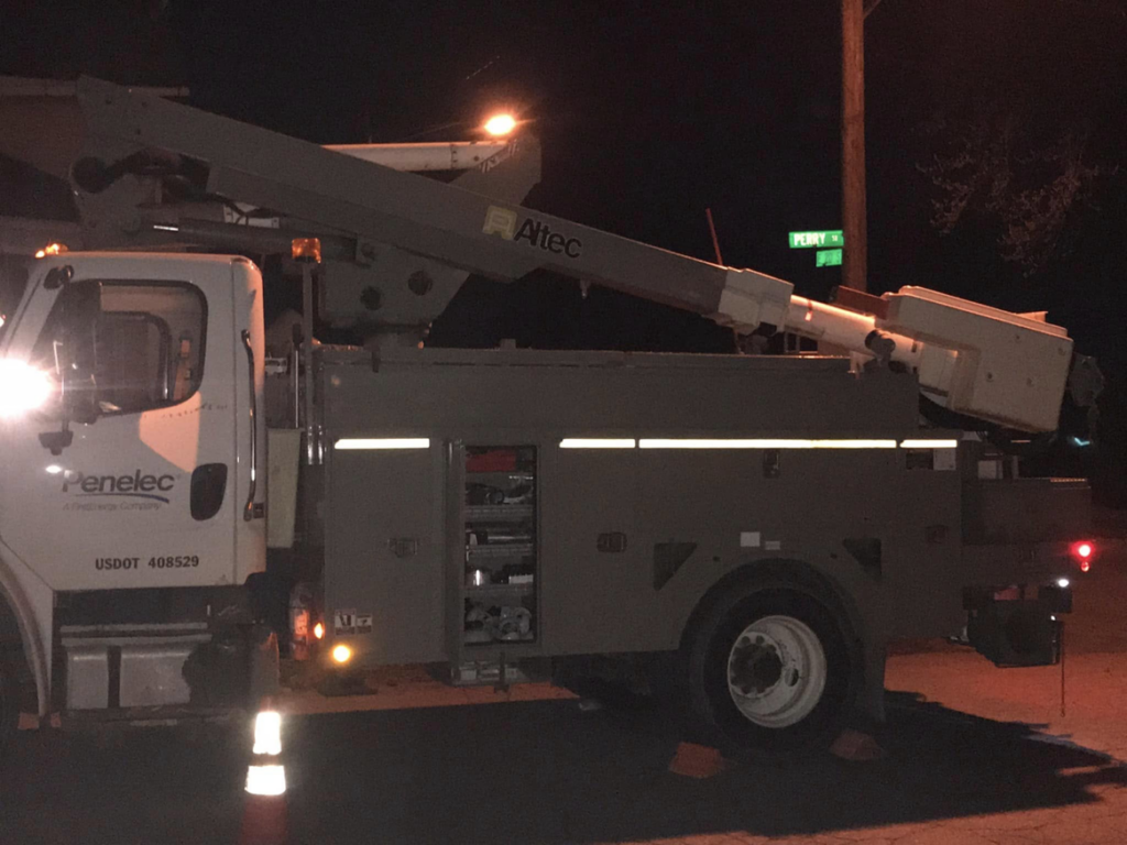 A utility bucket truck with its arm extended, performing electrical work at night for DRS Electric Co. in Erie, PA.