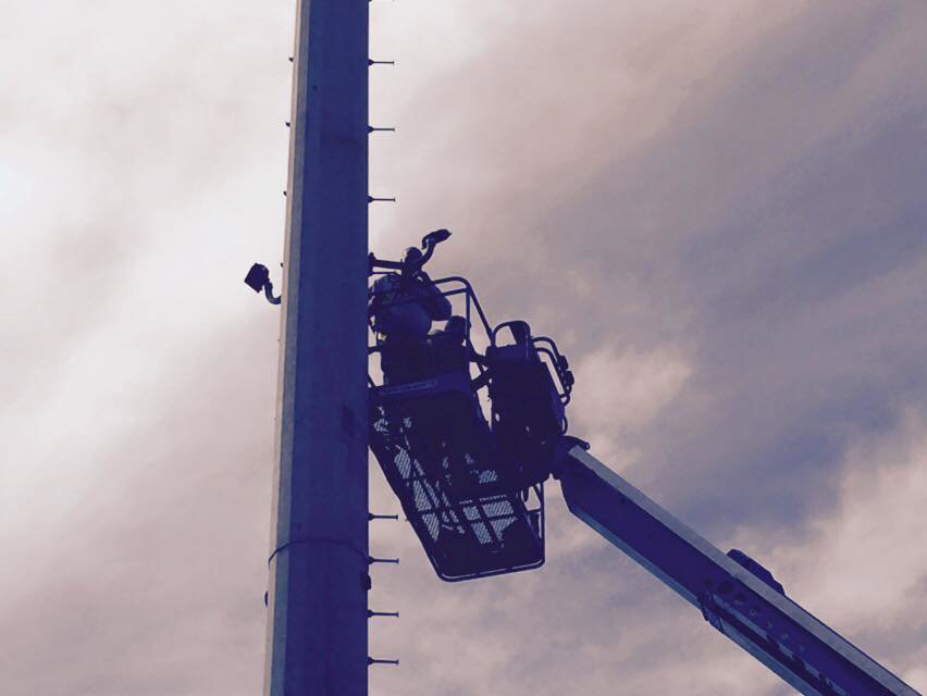 Electricians performing utility pole work from a boom lift for Spark Electric LLC in Kenai, AK.
