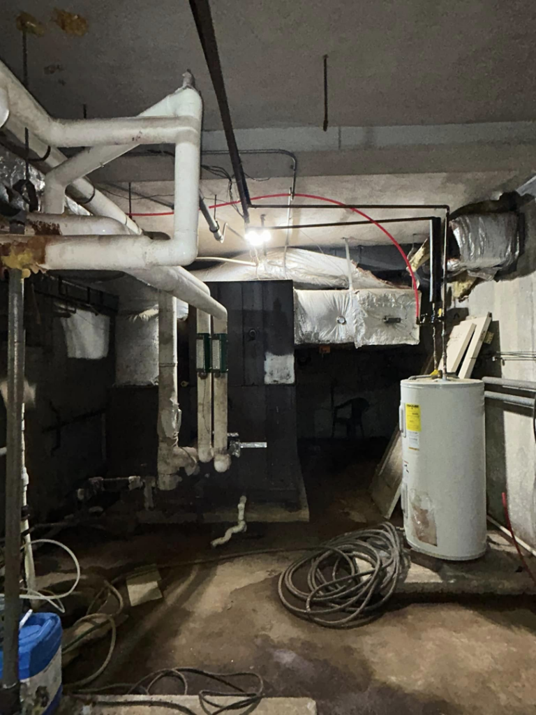 Utility room with various pipes, water heater, and HVAC equipment, serviced by Comfy Cool HVACR in Newport News, VA.