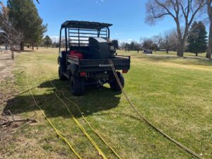 A UTV equipped with pest control hoses and equipment in a grassy area, ready for a job by No Moore Pests in Pueblo, CO.