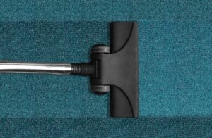 A vacuum cleaner head cleaning a blue carpet, leaving a distinct clean strip, by Hillsboro Carpet Cleaning in Hillsboro, OR.