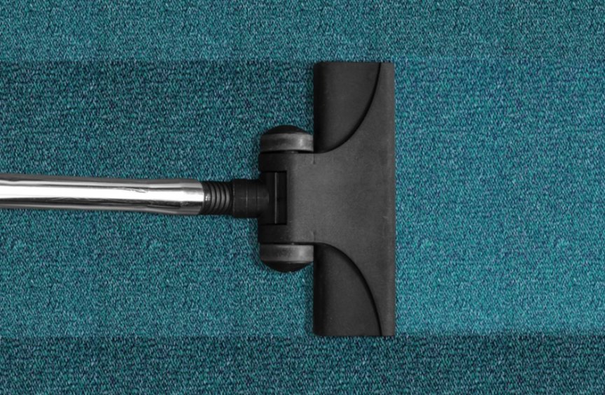 A vacuum cleaner head cleaning a blue carpet, leaving a distinct clean strip, by Hillsboro Carpet Cleaning in Hillsboro, OR.