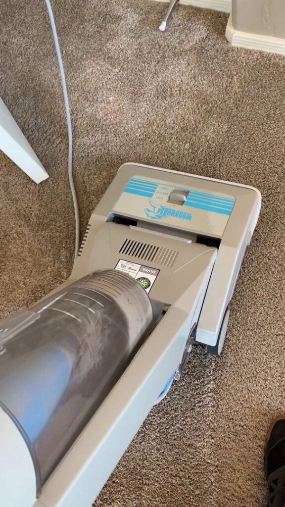 A vacuum cleaner on a carpet, showing collected dirt, part of the carpet cleaning process by Soft N Dry in Tucson, AZ.