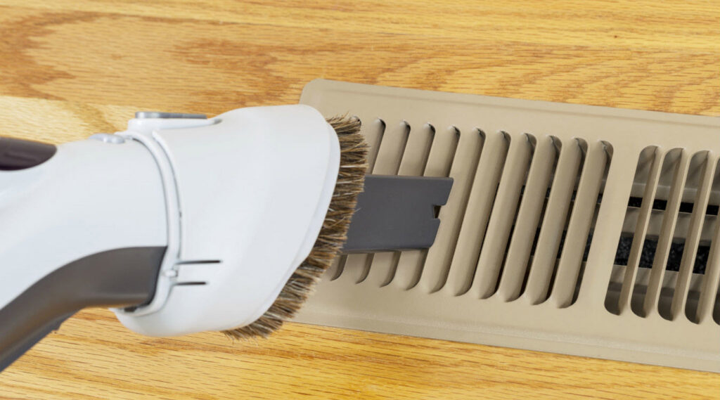 A vacuum cleaner attachment cleaning a floor air duct vent by Wright Way Air Duct Cleaning in Streamwood, IL