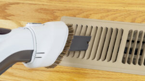 A vacuum cleaner attachment cleaning a floor air duct vent by Wright Way Air Duct Cleaning in Streamwood, IL