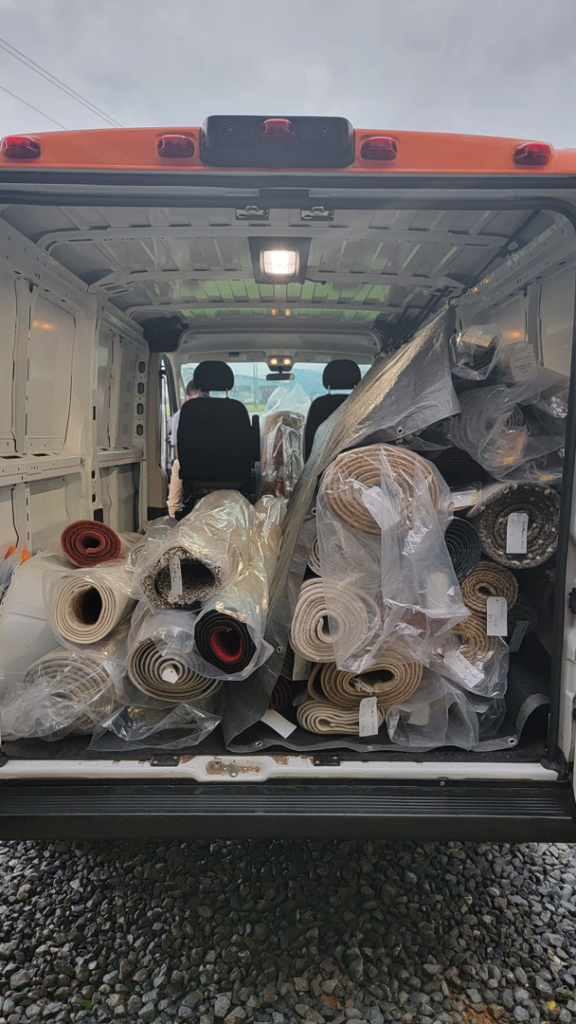 A delivery van filled with numerous rolled-up carpets and rugs for Advanced Cleaning Systems in Atlanta, GA.