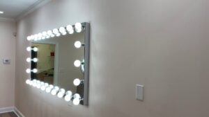 A large vanity mirror with multiple exposed light bulbs, expertly installed by Harbour Electric in Wilmington, NC.