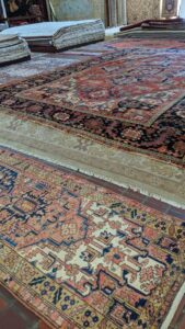 Various patterned rugs laid out on the floor, showcasing options at Woven Treasures, Inc in Mobile, AL.