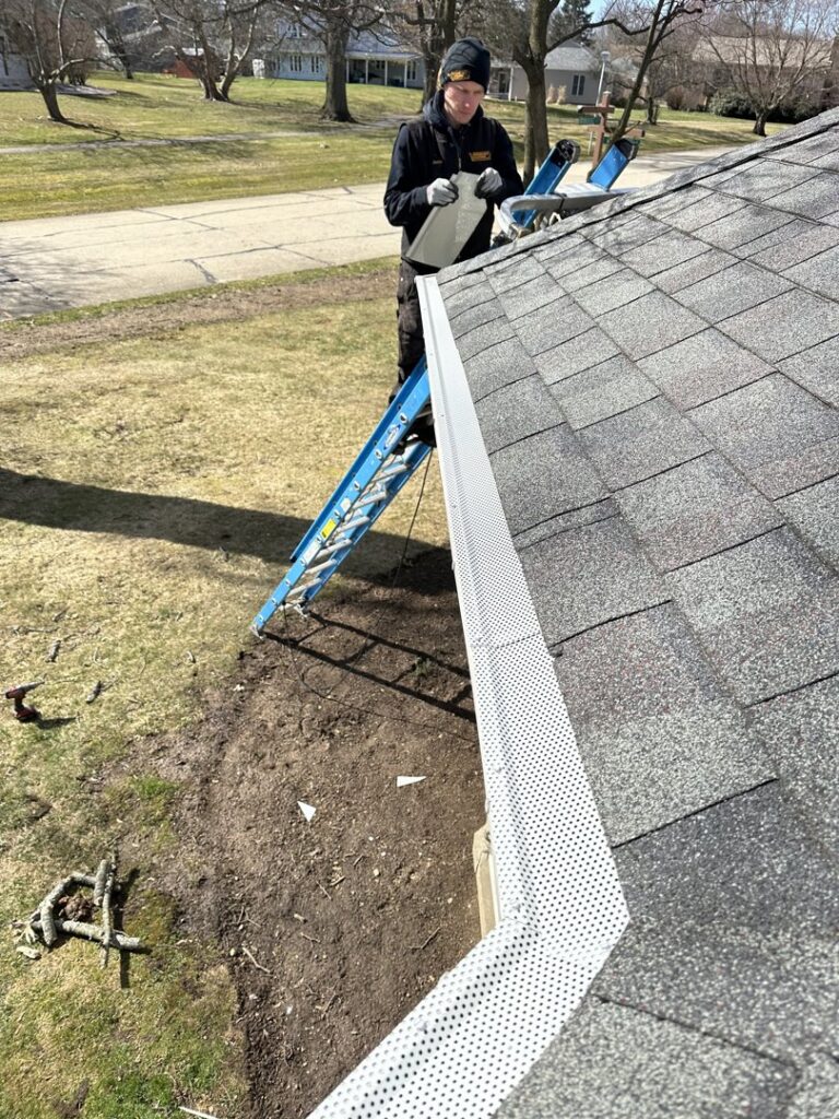 A Varment Guard technician installing protective gutter guards on a roof to prevent wildlife entry in Danville, IN.