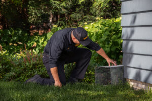 A Varment Guard technician placing a wildlife trap next to a residential home in Danville, IN.