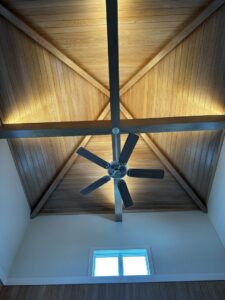 Vaulted wooden ceiling with a modern ceiling fan and integrated uplighting installed by Ampler Electrical Services in Wilmington, NC.