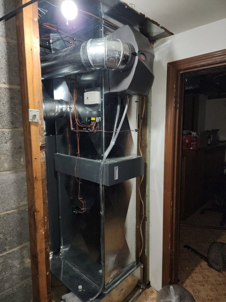A vertical furnace or air handler unit with connected ductwork, installed within a wall cavity by Evergreen HVAC Comfort Solutions in Milwaukee, WI.