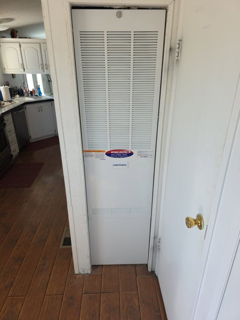 A vertical furnace unit installed in a closet, featuring the Nevada Heating Reno sticker in Sparks, NV.