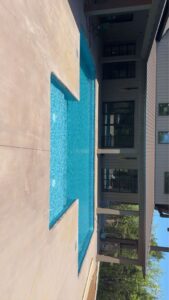 A vertical view of an L-shaped inground pool with clear blue water and surrounding concrete, installed by Riverstone LLC in Bowling Green, KY.