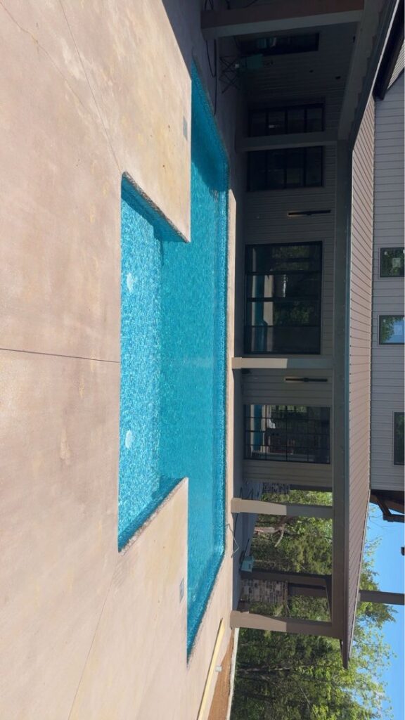 A vertical view of an L-shaped inground pool with clear blue water and surrounding concrete, installed by Riverstone LLC in Bowling Green, KY.