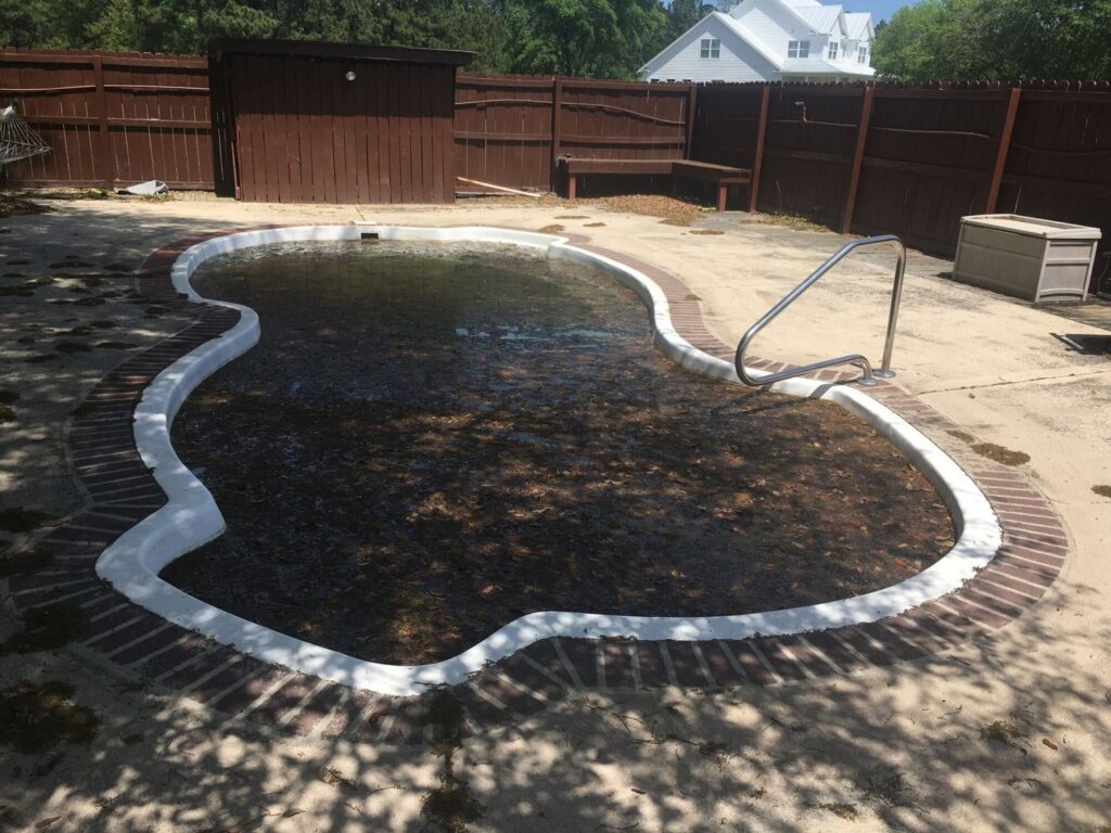 A very dirty, leaf-filled swimming pool in need of cleaning by Pool King in Southhold, NY.