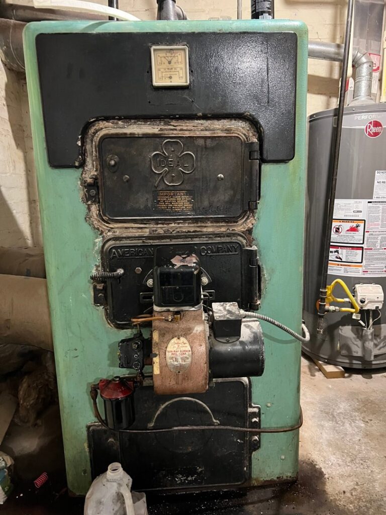 A vintage heating boiler system with a water heater in the background, serviced by ECA DuctWorks in Reston, VA